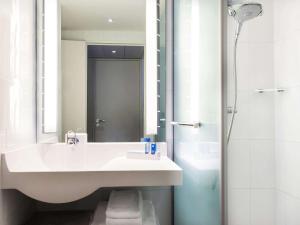 a white bathroom with a sink and a shower at Novotel Paris Pont De Sevres in Sèvres