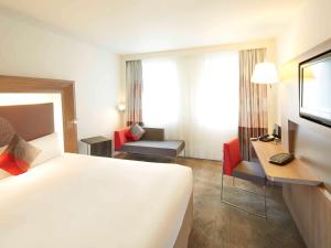 una camera d'albergo con un grande letto e una scrivania di Novotel Paris Pont De Sevres a Sèvres