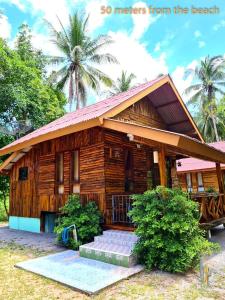 una pequeña casa de madera con porche en Sangjun On Beach Resort, en Bang Saphan