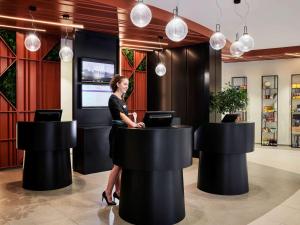 a woman standing at a counter in a lobby at Mercure Paris La Défense in Courbevoie