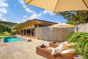 une maison avec une piscine et un parasol dans l'établissement Sungulwane Private Game Lodge, à Hluhluwe