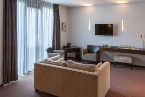 a living room with a couch and a television at Best Western Hotel Nobis Eindhoven-Venlo A67 in Asten