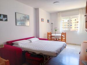 - une chambre avec un lit et un canapé rouge dans l'établissement Apartamento Hibisco , Primera Línea de Playa, à Almuñécar