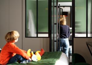 un jeune garçon assis sur un lit avec des canards farcis dans l'établissement Hotel Bridget, à Paris