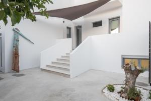 une maison blanche avec un escalier et un arbre dans l'établissement Rivière Residence Paros, à Náoussa