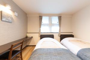 a bedroom with two beds and a desk and a window at スタジオーネ 箱根強羅 West - Stagione Hakone Gora West in Gora