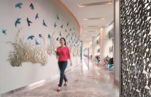 a woman walking down a hallway with birds on the wall at JEN Singapore Orchardgateway by Shangri-La in Singapore