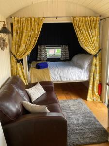 a living room with a couch and a bed at Willow Brook Shepherd Hut in Sidmouth