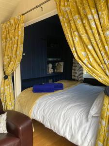 a bedroom with a bed with yellow curtains at Willow Brook Shepherd Hut in Sidmouth