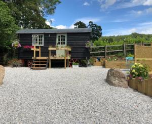 a black tiny house in a gravel yard at Willow Brook Shepherd Hut in Sidmouth