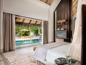 a bedroom with a bed and a pool at JOALI Maldives in Raa Atoll