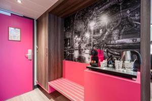 a room with pink walls and a wall with a wallpaper at Hôtel Le Kennedy, Clermont-Ferrand, The Originals Relais in Clermont-Ferrand