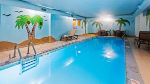 una piscina en un hotel con palmeras en la pared en Denver North Hotel, en Thornton