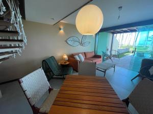 uma sala de estar com uma mesa de madeira e cadeiras em Pontal dos Carneiros Beach Bungalows em Praia dos Carneiros