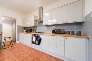 een keuken met witte kasten en een houten vloer bij Mercy Way 4 Bedroom-6 Beds-Central Hull-Sleeps 8 in Hull