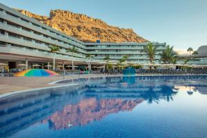 a hotel with a swimming pool with a mountain in the background at Radisson Blu Resort & Spa, Gran Canaria Mogan in Puerto de Mogán