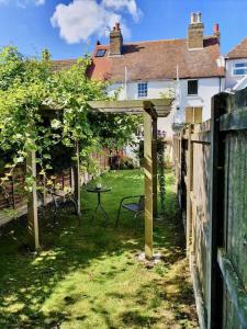 a garden with a wooden pergola and a table in a yard at The Writer's Cottage in Deal