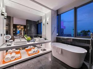 西安的住宿－西安西咸诺富特酒店，带浴缸和两个盥洗盆的浴室以及大窗户。