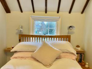 a bed with two pillows and a window in a room at The Writer's Cottage in Deal