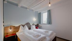 Schlafzimmer mit einem Bett mit weißer Bettwäsche und Kissen in der Unterkunft Bett & Berg Bad Ischl, Self Check-In in Bad Ischl