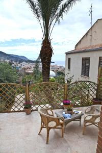 een patio met een palmboom en een tafel en stoelen bij La Casa della Luna (by Vacation Service) in Cefalù