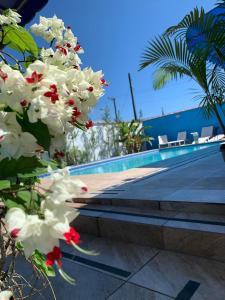 a bunch of white orchid flowers next to a swimming pool at Residencial Rosi in Caraguatatuba