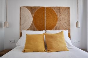 a bed with two yellow pillows and a headboard at Slow Home Apartments in Valencia