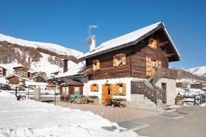 een houten huis met sneeuw op het dak bij Baita sulle Alpi in Livigno