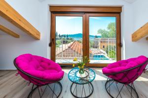 dwa różowe krzesła w pokoju z oknem w obiekcie Villa Mia w mieście Trsteno