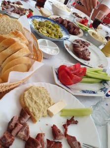a table topped with plates of food with meats and vegetables at Casa Brâncușiana in Târgu Jiu