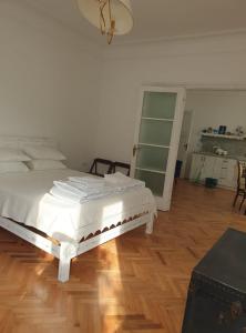 a bedroom with a white bed and a wooden floor at Апартамент BOHO CHIC 2 Free parking in Varna City