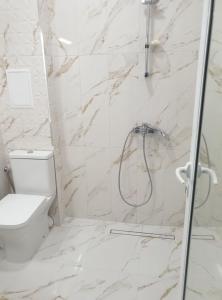 La salle de bains blanche est pourvue d'une douche et de toilettes. dans l'établissement Апартамент BOHO CHIC 2 Free parking, à Varna