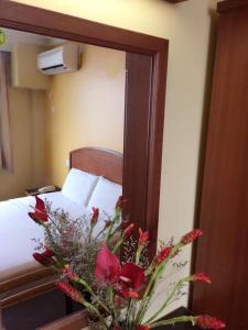 納閩的住宿－Hotel Millenium，一间卧室配有一张带镜子和鲜花的床