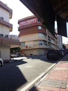 a building on a street with cars parked in front of it at Hotel Millenium in Labuan