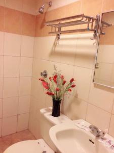 un bagno con un vaso di fiori su un WC di Hotel Millenium a Labuan