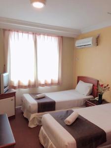 una camera d'albergo con due letti e una televisione di Hotel Millenium a Labuan