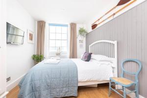 a bedroom with a white bed and a blue chair at Little Gem in Swanage