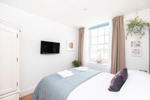 a white bedroom with a bed and a window at Little Gem in Swanage