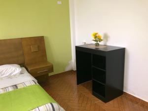 ein Schlafzimmer mit einem Bett und einem Schreibtisch mit einer Blumenvase darauf in der Unterkunft Figaro Hotel Samana in Santa Bárbara de Samaná