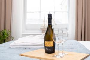 a bottle of wine on a cutting board with two wine glasses at Little Gem in Swanage
