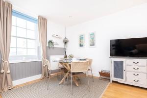 a dining room with a table and a tv at Little Gem in Swanage
