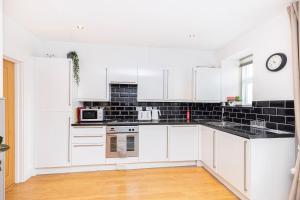 a kitchen with white cabinets and a clock on the wall at Little Gem in Swanage