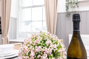 a bottle of wine and a bouquet of flowers on a table at Little Gem in Swanage