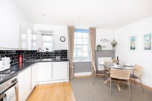a kitchen with white cabinets and a table with chairs at Little Gem in Swanage