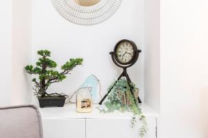 a clock sitting on a white cabinet with plants at Little Gem in Swanage
