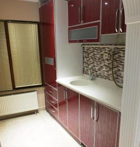 a kitchen with red cabinets and a sink and a window at Heykel Residence in Bursa