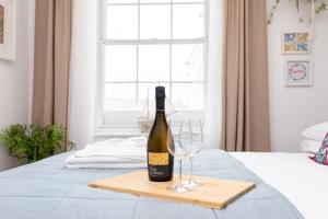 a bottle of wine and two glasses on a bed at Little Gem in Swanage