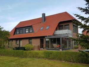 a large house with a red roof and a yard at Ferienwohnungen Haus Elena 45241 in Ditzum