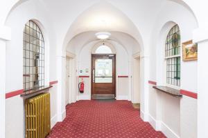 an empty hallway with a red floor and a door at Little Gem in Swanage