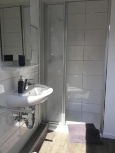 ein weißes Bad mit einem Waschbecken und einer Dusche in der Unterkunft Apartment Marit in Norden
